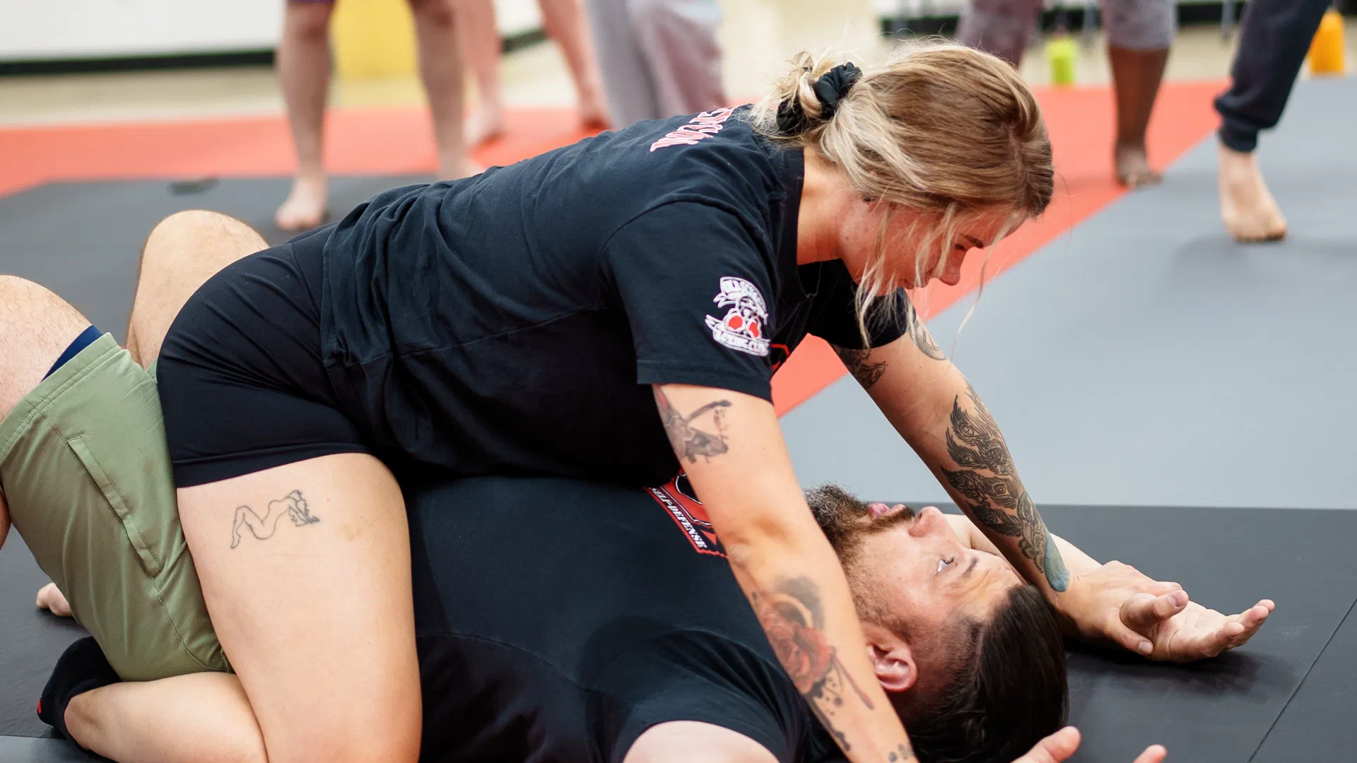 Journey BJJ coach demonstrating arm-pin defense with Madison self-defense student