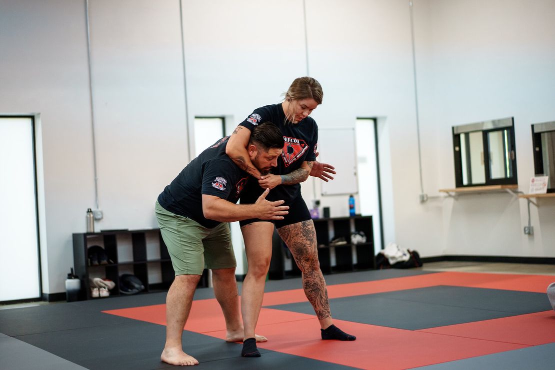 Journey BJJ instructor demonstrating headlock defense technique with Madison self-defense student