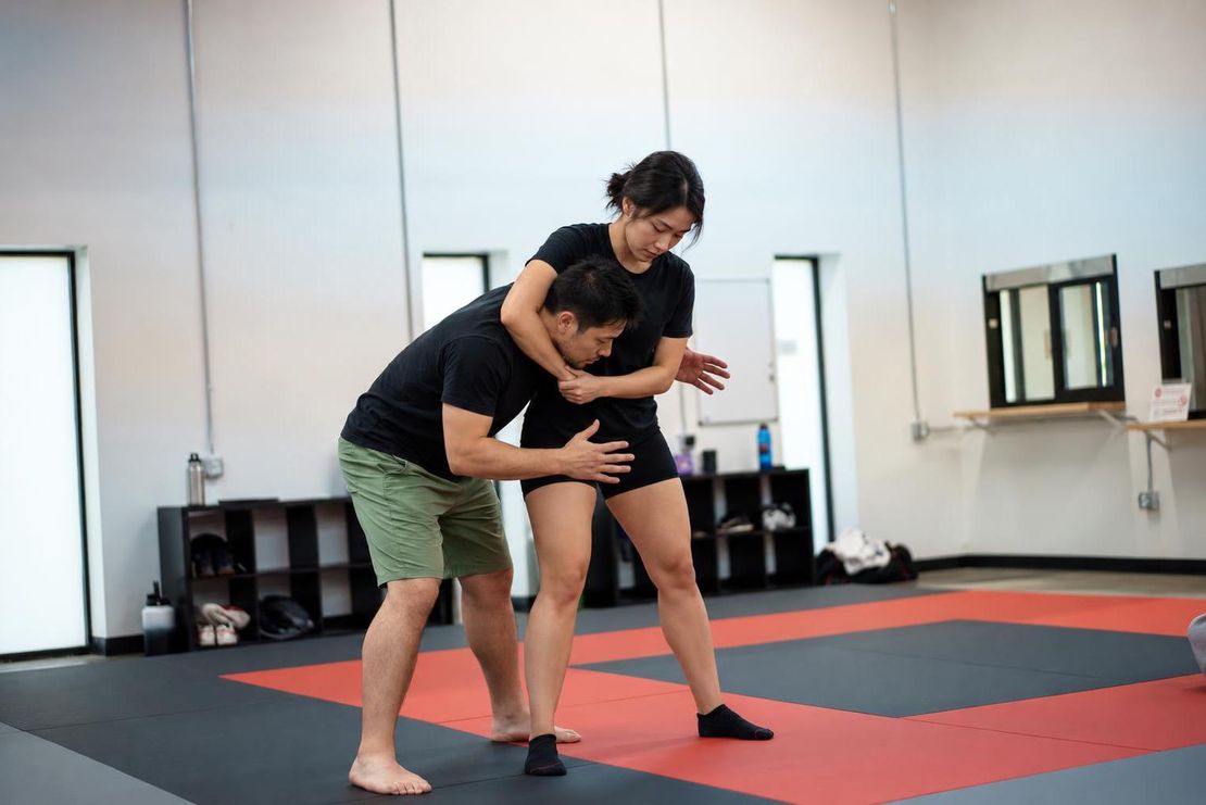 Journey BJJ instructor demonstrating headlock defense technique with Madison self-defense student