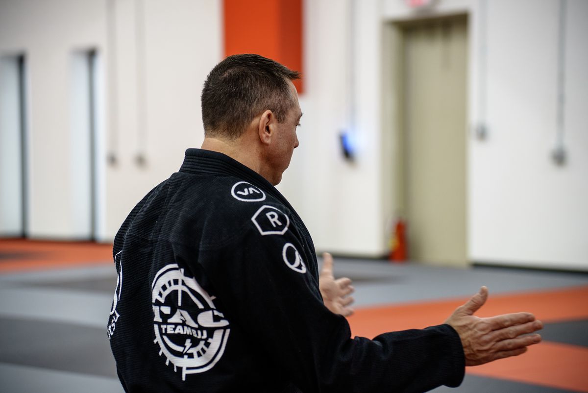 black gi instructor teaching class mat view