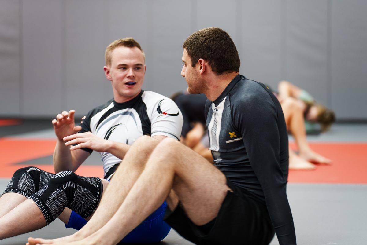 Two adults talking on the mat between rounds