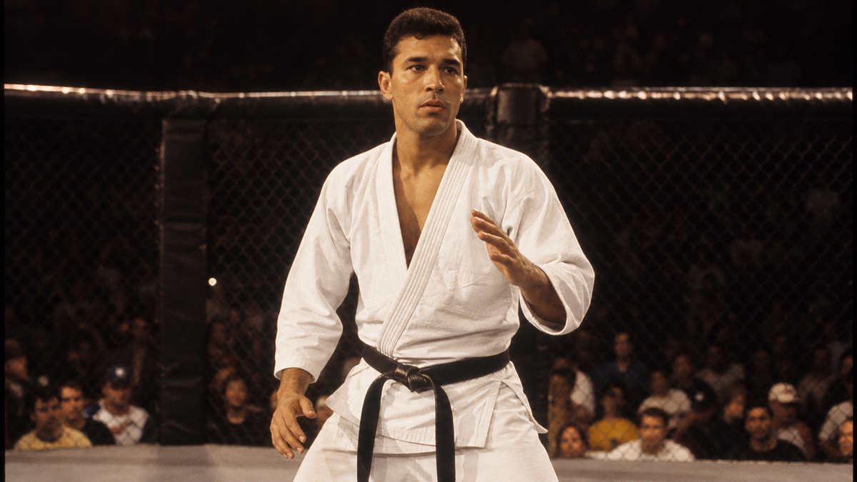 Royce Gracie in white BJJ gi and black belt inside the original UFC 1 octagon