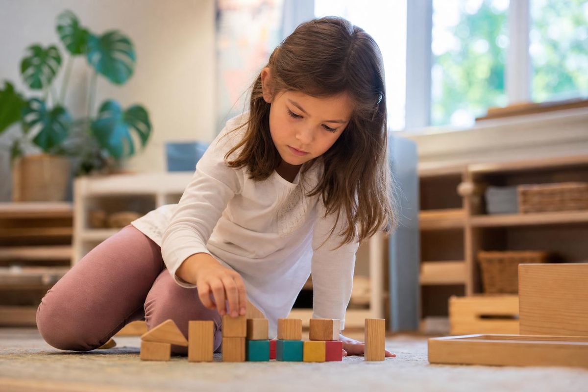 A calm elementary-age child mid-task in a bright room, low angle, conveying the idea of holding a plan in mind