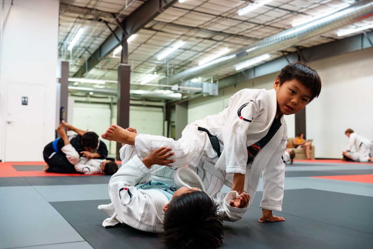 Two kids in white gis drilling a guard-pass cooperatively on the Journey BJJ mats