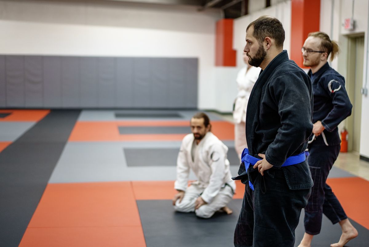 Adults in a Journey BJJ evening class, ordinary weeknight energy, mixed ages and body types