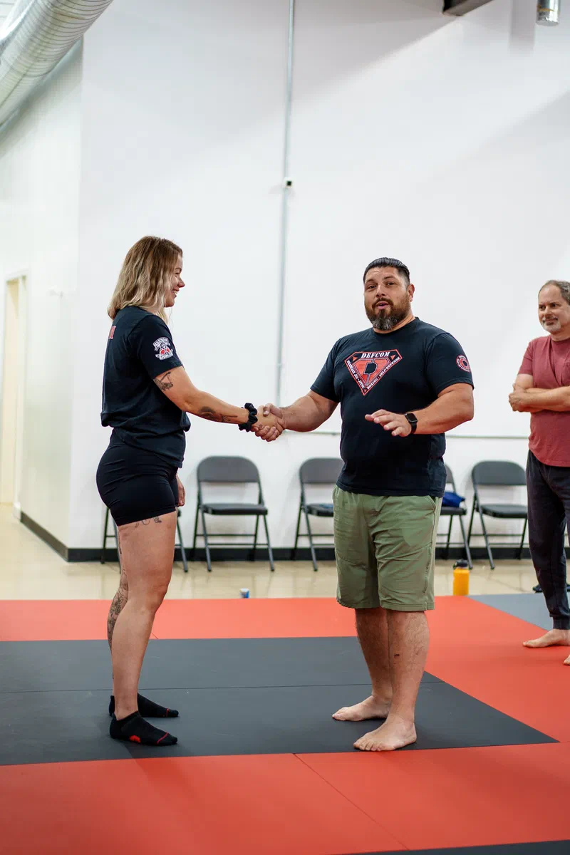 Coach guiding Madison adult students through headlock escape during Journey BJJ combatives class