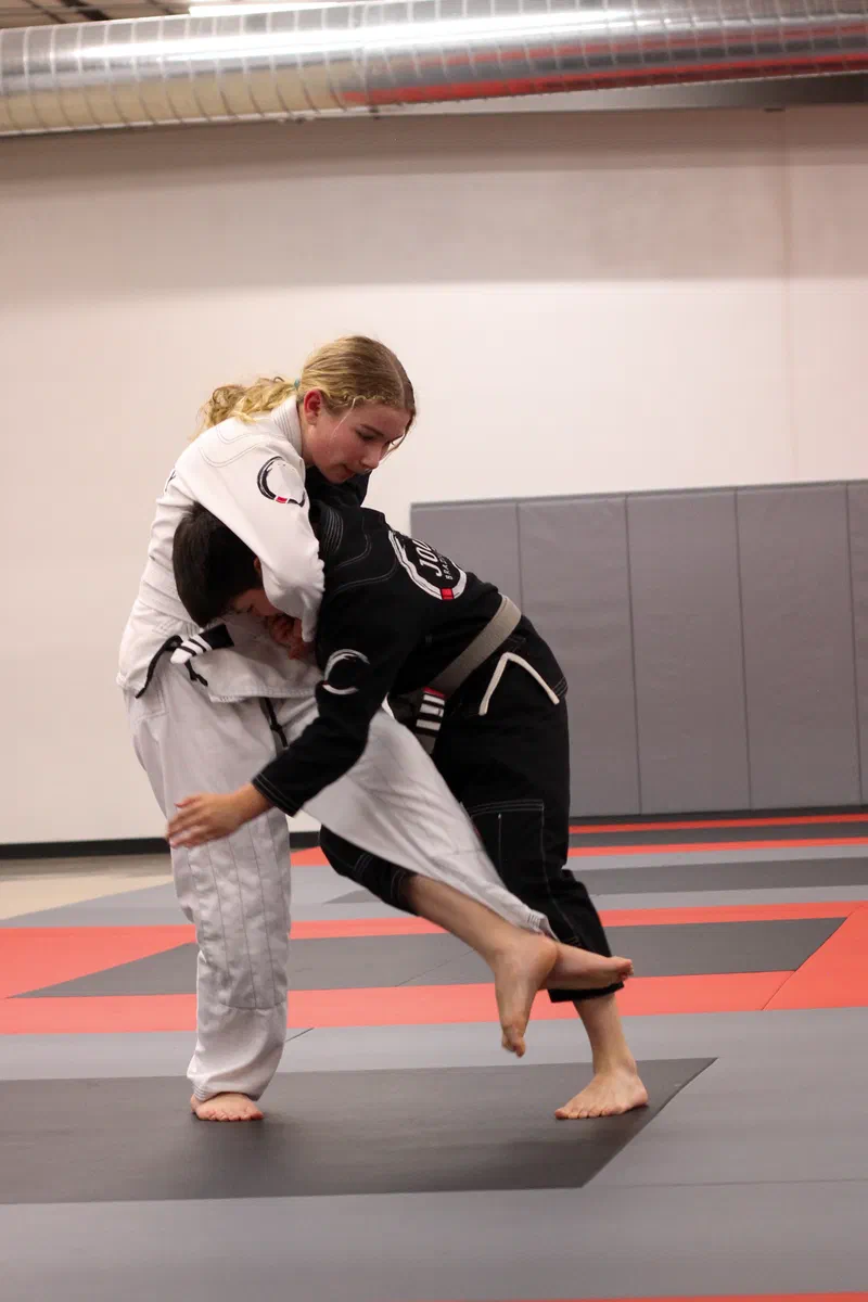 Children practicing Brazilian jiu jitsu techniques in a safe, supervised environment