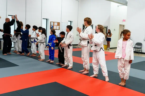 Kids class lined up clapping with instructor at Journey BJJ Madison