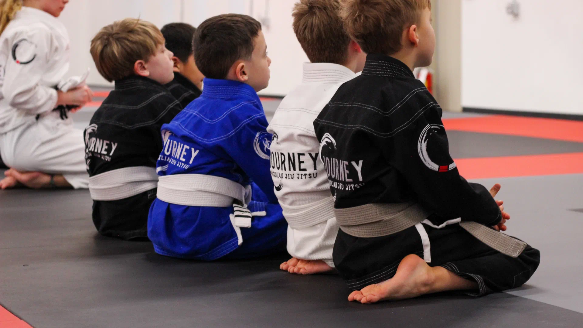Kids sitting attentively learning brazilian jiu jitsu in a kids bjj class in Madison, WI