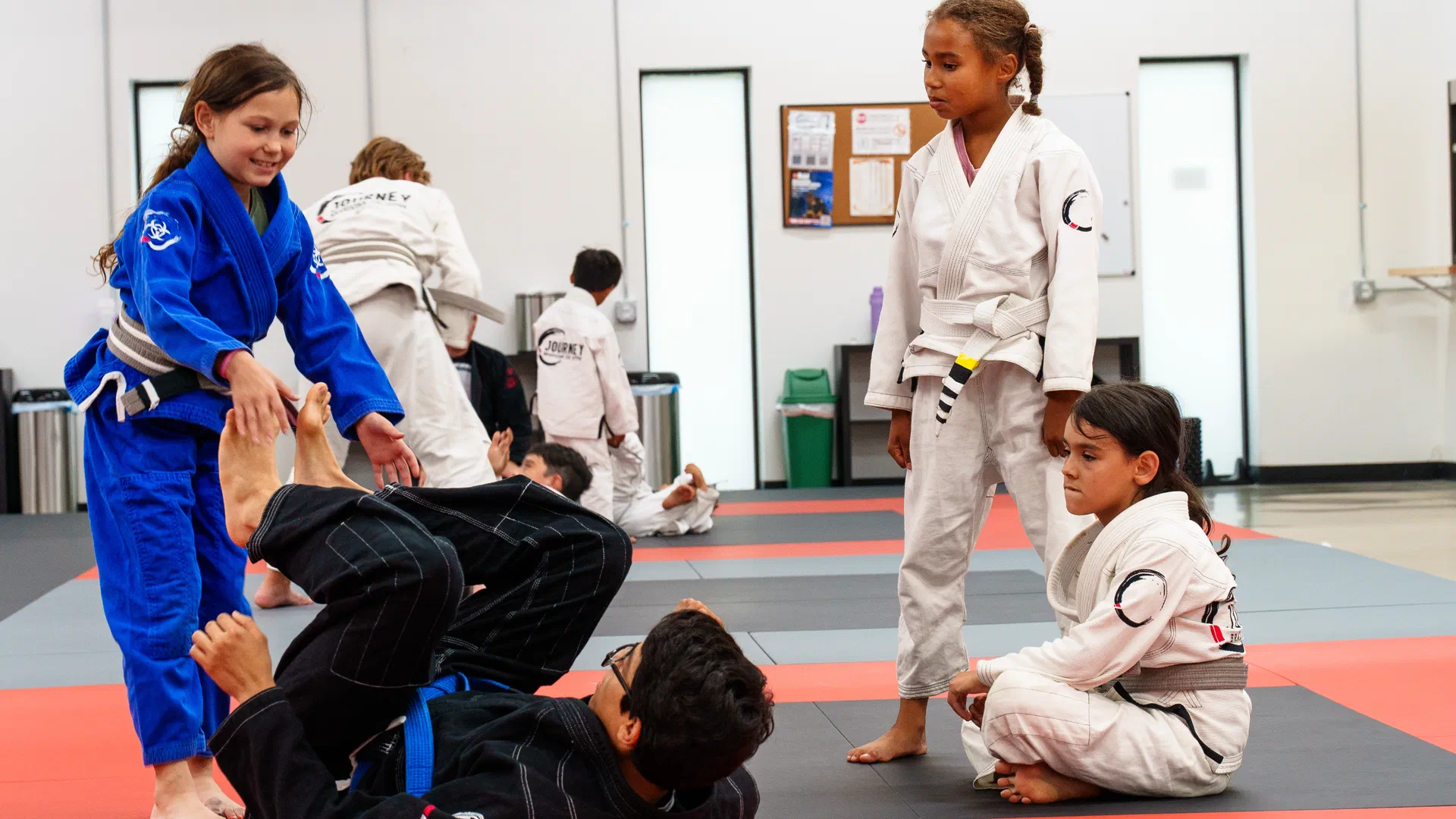 Children practicing Brazilian jiu jitsu techniques in a safe, supervised environment