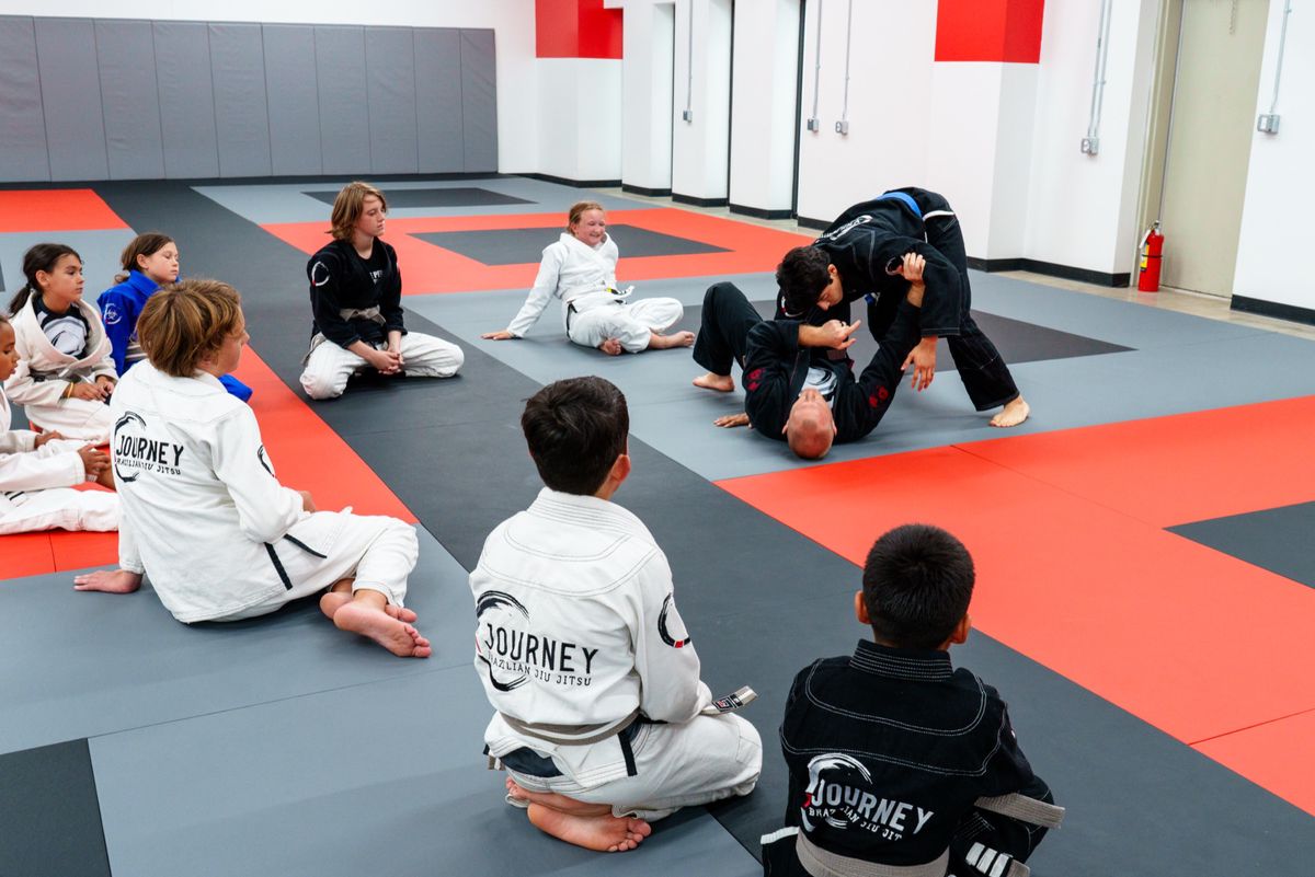 kids watching instructor demo on mat
