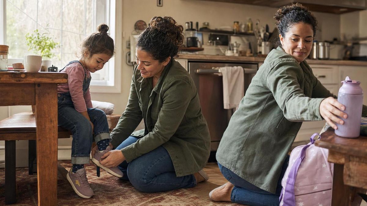A parent and child at a kitchen table working through a two-step task together, warm daylight