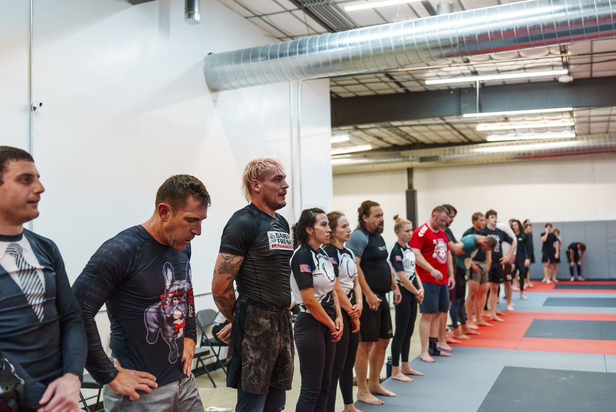 Adult BJJ class at Journey, upright drilling pairs on the mat, one pair mid-handshake, a range of ages and body types visible